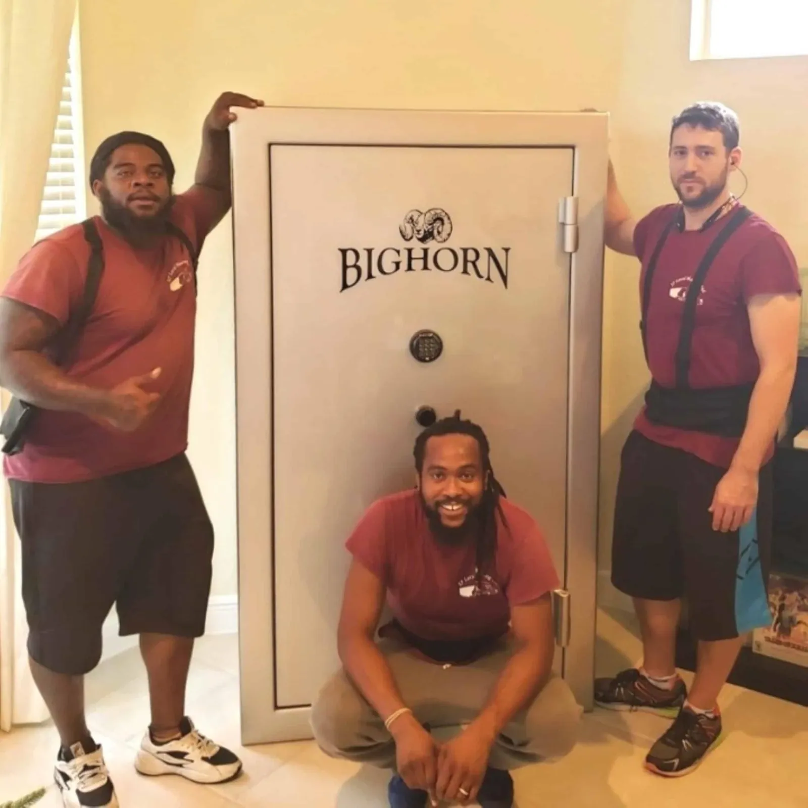 Three SF Local Moving movers in maroon company shirts with a large safe they moved
