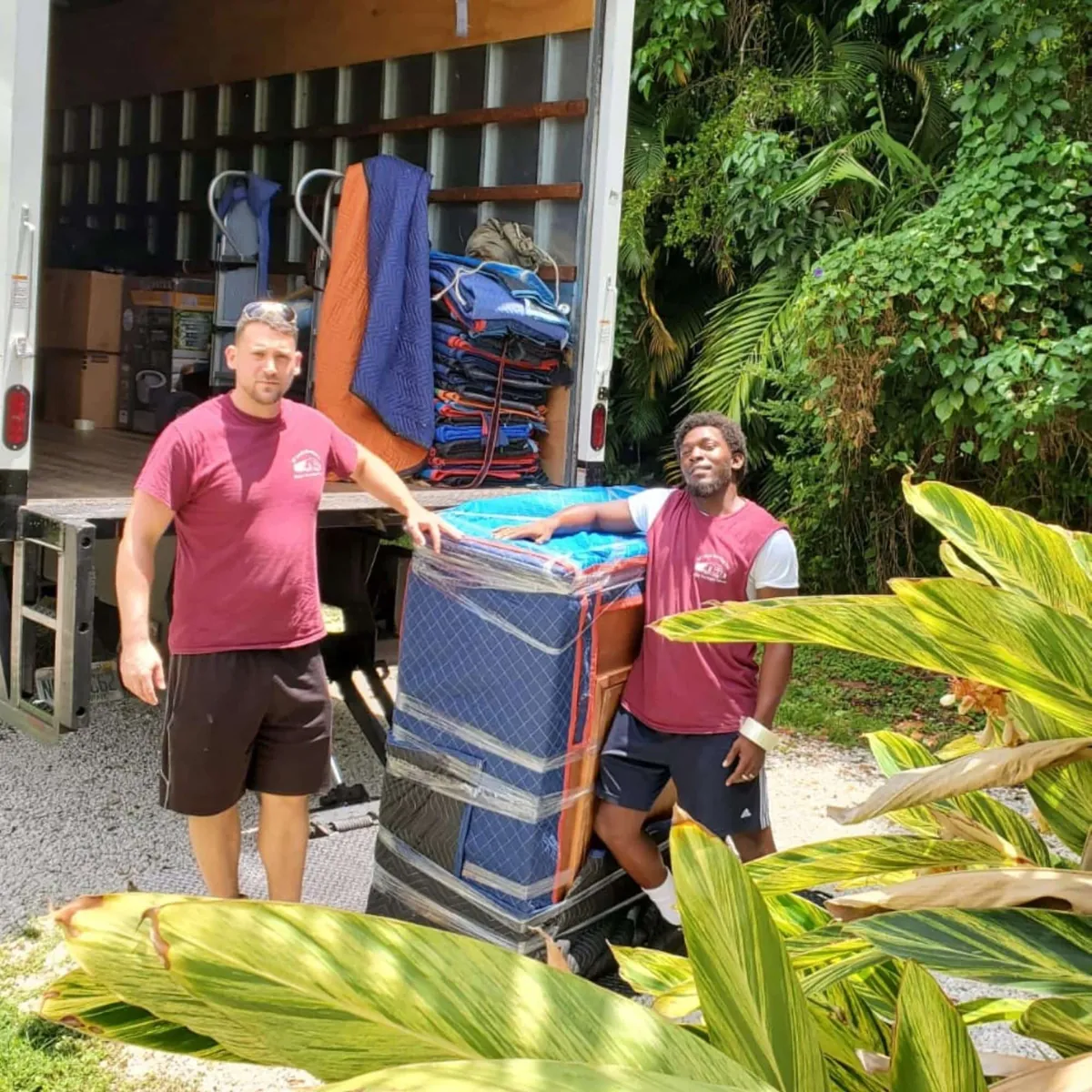 Two SF Local movers at the back of a loaded truck with blanket-wrapped furniture