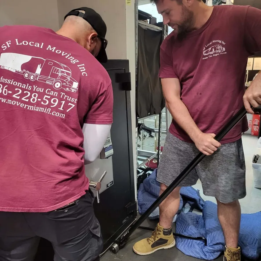 SF Local movers maneuvering a safe, company logo on the back of the shirt