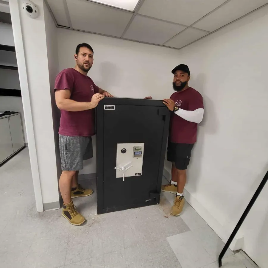 Two SF Local movers with a black safe they placed in an office