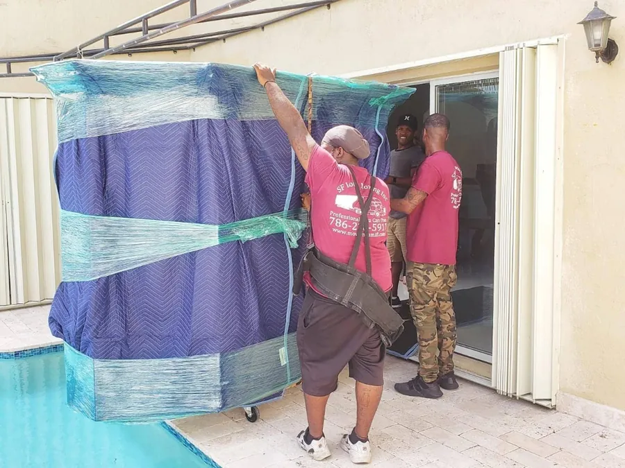 SF Local movers with a wrapped item on a dolly next to a pool