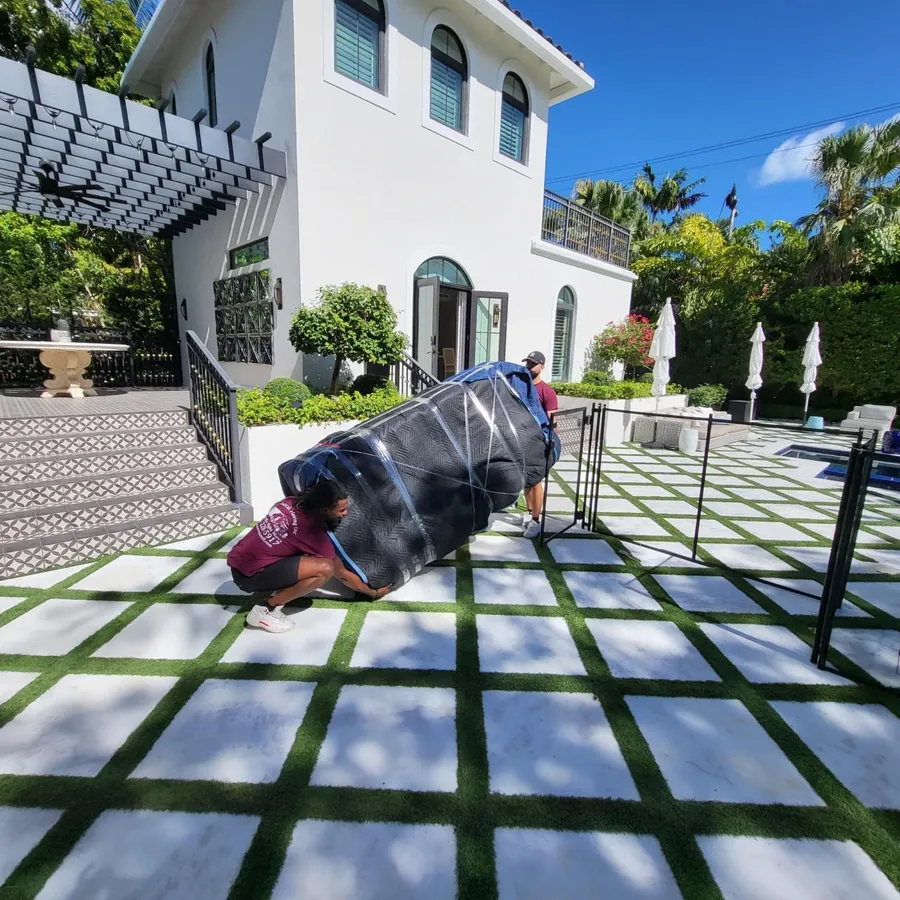 Mover wrapping a large item on the patio of a white Mediterranean home