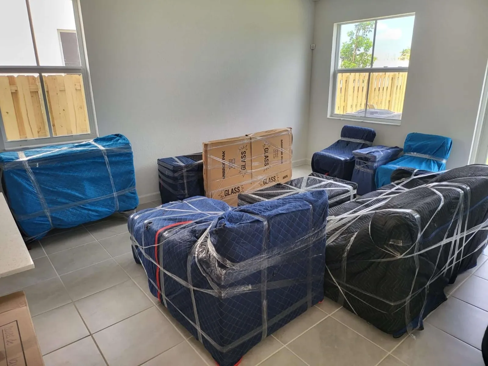 Living room full of furniture wrapped in blue moving blankets